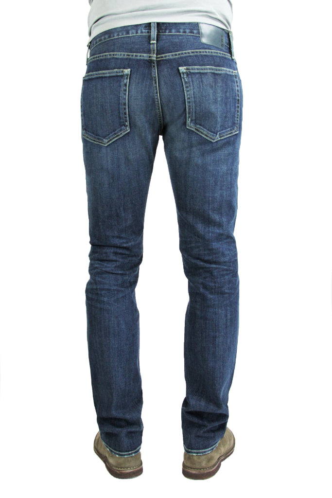 Back of S.M.N Studio's Hunter in Odyssey Men's Jeans - Slim fit medium vintage indigo washed denim contrasted by light fading throughout the jeans including whiskers and honeycombs
