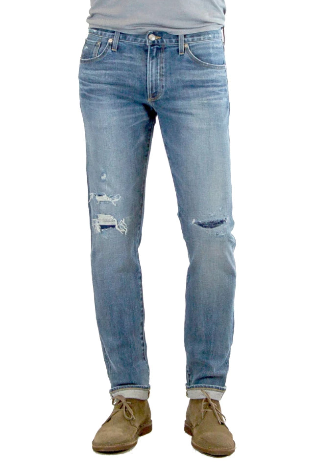 S.M.N Studio's Hunter in Baker Men's Jeans - Slim fit stretch selvedge denim in a medium wash denim finished with fades and distessing, repair detail on knees